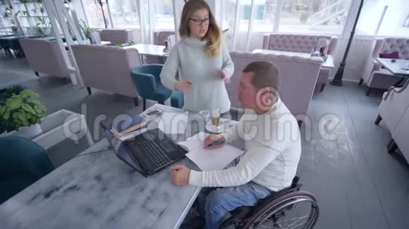 家庭教育成功的残疾人在轮椅上与教师女性使用现代计算机技术视频的预览图