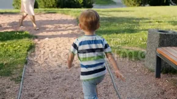 4k视频可爱的笑着蹒跚学步的男孩在公园里向母亲跑和远离母亲视频的预览图