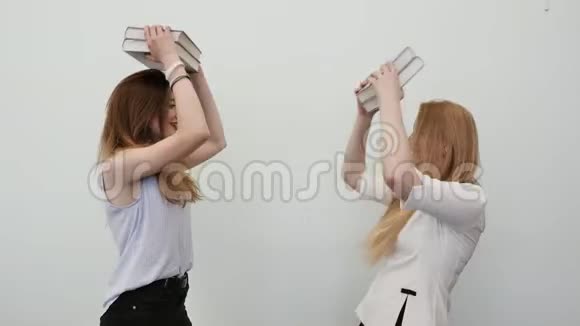 两个女学生玩着书把它们抱在头上视频的预览图
