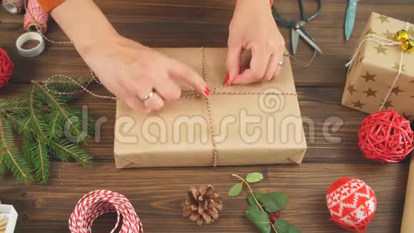 女人的手在黑暗的木制背景上包装圣诞礼物视频的预览图