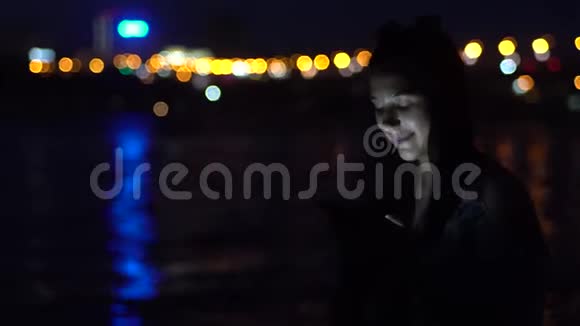 这个女孩在城市的背景下使用一个萨特电话晚上心情很好4K视频的预览图