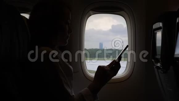 一个女人独自坐着智能手机的飞机靠窗聊天视频的预览图