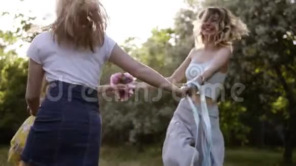 快乐的女朋友一起在户外玩圆舞牵着手明媚阳光明媚的一天慢动作视频的预览图