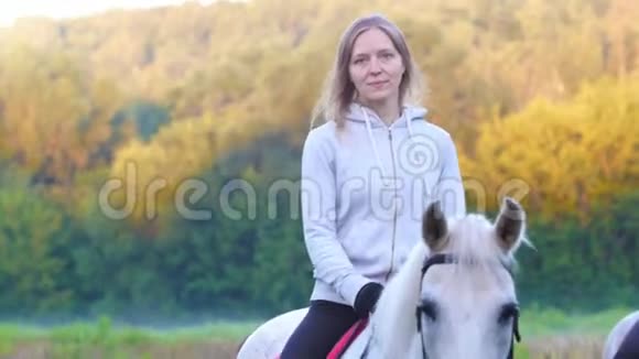 年轻的金发女人骑着一匹大自然中的白马视频的预览图