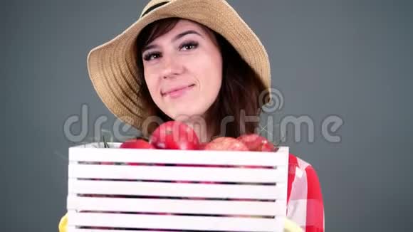穿着格子衬衫戴着手套戴着白色木箱戴着红熟的美丽微笑的女农民画像视频的预览图