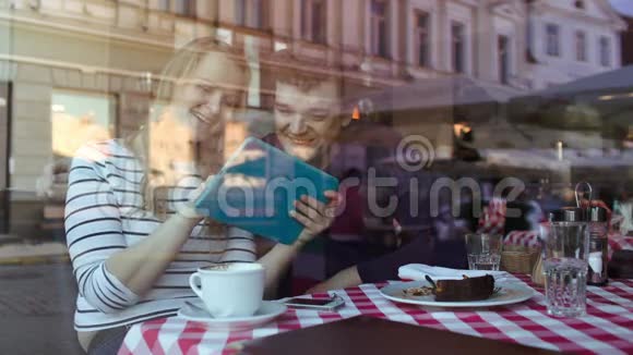 一对在咖啡馆里玩平板电脑的年轻情侣视频的预览图