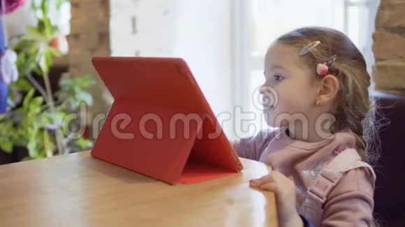 可爱的小女孩在数码平板电脑上玩游戏视频的预览图