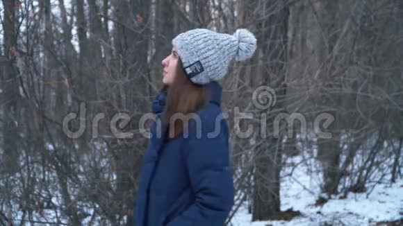 穿着夹克的小女孩在森林里冬天四处张望冬天森林里美丽的一天视频的预览图