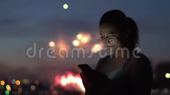 一个女孩在烟火中使用智能手机心情很好慢动作高清高清视频的预览图