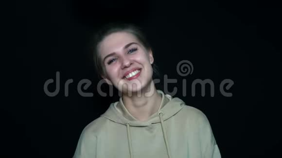 一个年轻女人在黑色背景上笑的特写肖像她很积极视频的预览图