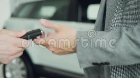 在汽车陈列室成功成交后收车钥匙并与销售员握手视频的预览图