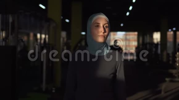 年轻的穆斯林运动女孩戴着头巾来到健身房训练慢节奏视频的预览图