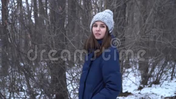 美丽的女孩穿蓝色针织围巾户外冬季森林看着摄像机的漂亮女孩视频的预览图