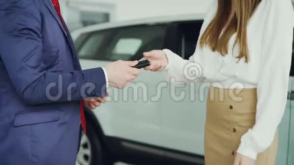 苗条的年轻女子从西装销售员那里得到汽车钥匙然后和他握手庆祝成功的交易视频的预览图