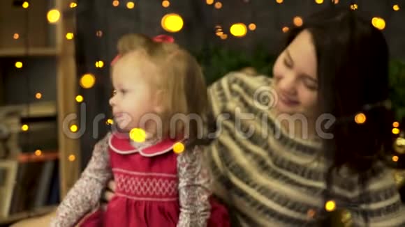 年轻的迷人的微笑的女人妈妈带着一个快乐的甜美的孩子在黄色后面的美丽的新年工作室里视频的预览图