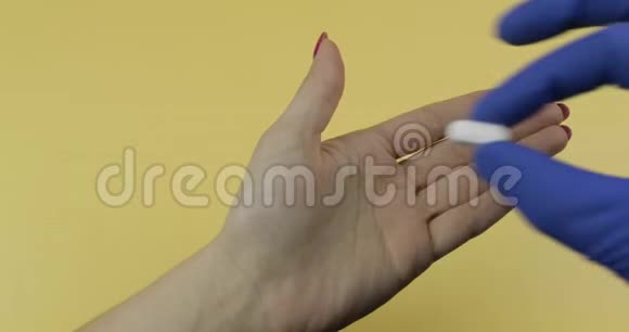 穿着蓝色医用手套的医生手把一颗白色药丸放进女人手里视频的预览图