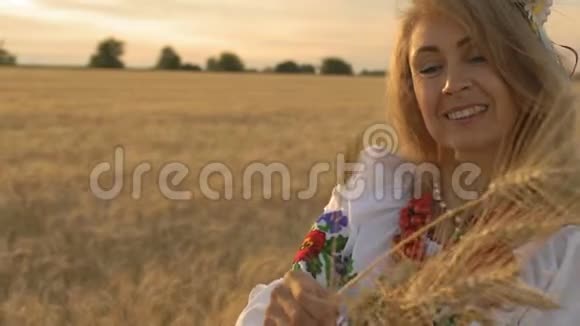 慢动作特写美丽的女人在国家服装在麦田看麦穗在手和微笑视频的预览图