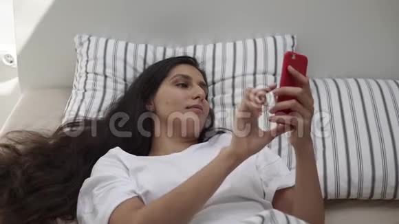 被唤醒的年轻女子正在她的智能手机上打字躺在床上视频的预览图