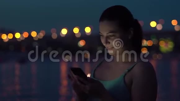 这个女孩晚上在城市里散步时使用智能手机心情很好高清高清视频的预览图