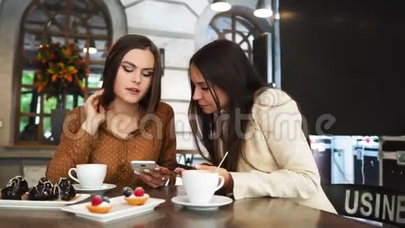 一群穿着办公室服装的男人和女人坐在一张大桌子上的咖啡馆里用手机互相展示着有趣的事情视频的预览图