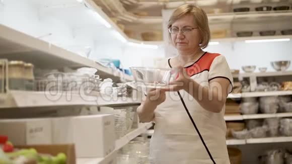 退休妇女在餐具店里手里拿着玻璃碗视频的预览图