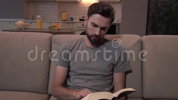 大胡子坐在沙发上看厚厚的书他翻开书页然后人类向左看继续阅读视频的预览图