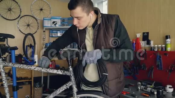 年轻的自行车修理车间的机械师正在修理自行车把一捆电线固定在自行车车架上视频的预览图
