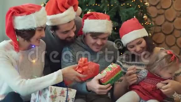 快乐漂亮的家庭夫妇和他们的朋友坐在一起给她不同的礼物和灯光视频的预览图