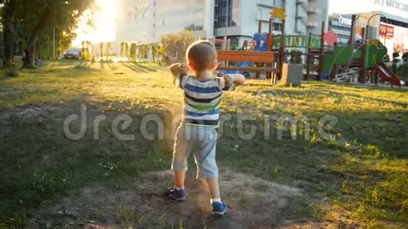 4K录像小托德尔男孩在公园操场上玩耍扔沙子视频的预览图