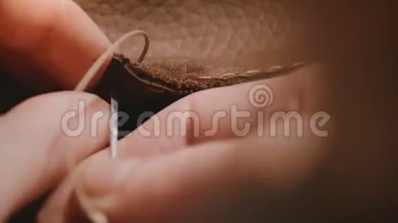 宏观特写详细拍摄女性手缝制手工粗糙边缘的皮包用针和蜡线视频的预览图