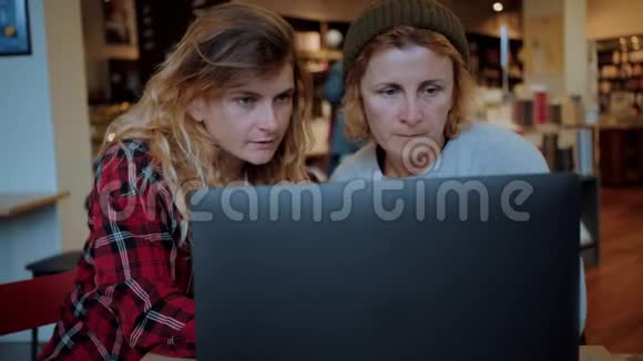 两个女人在咖啡馆或同事的笔记本电脑上工作视频的预览图