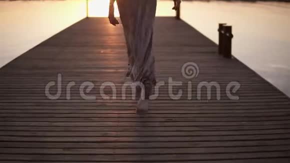 时尚美丽的女人棕色头发穿着优雅的灰色丝绸连衣裙走在码头上阳光在大海之上视频的预览图