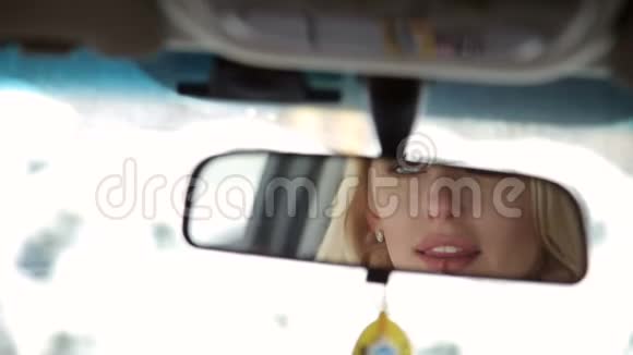 女孩在车里画嘴唇在镜子里倒影视频的预览图