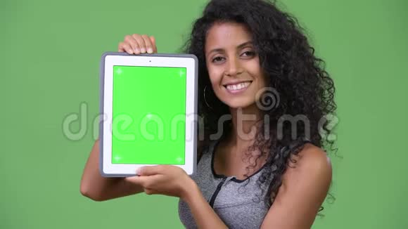 年轻漂亮的西班牙女人穿着运动服展示数字平板电脑视频的预览图
