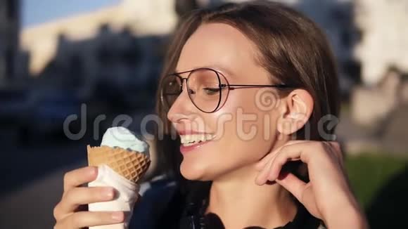 侧视镜头一个迷人的女孩在外面的街道上吃大白色冰淇淋穿现代衣服的年轻女子视频的预览图