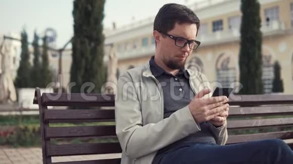 布鲁纳曼正坐在公园里用他的智能手机阅读信息和回答视频的预览图
