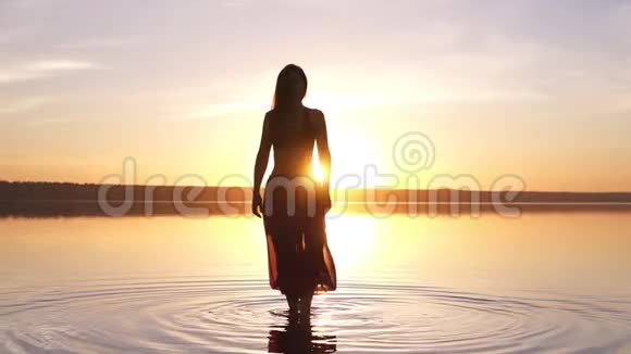 日落海滩上的美丽镜头女人在水中做瑜伽慢慢视频的预览图
