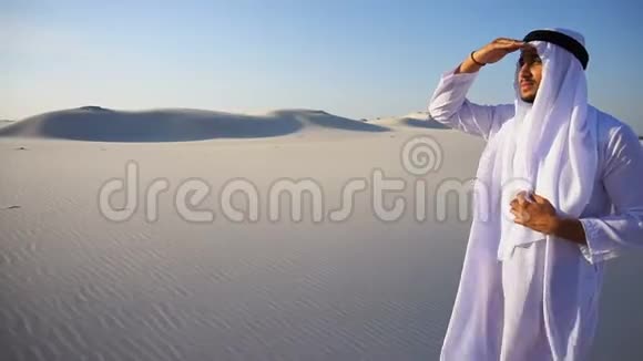 美丽的埃米尔谢赫在远处的骆驼商队中眺望在炎热的日子站在广阔的沙漠中视频的预览图
