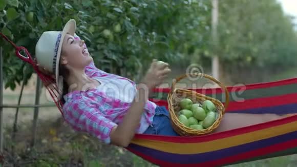 水果作物农民女孩喜欢在吊床上放松吃篮子里的苹果视频的预览图