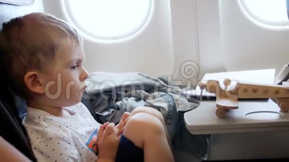 飞机飞行过程中玩具飞机坐在乘客座位上的小托德尔男孩4k视频视频的预览图