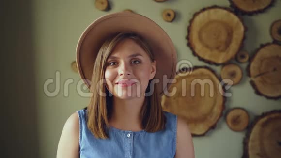 漂亮的年轻女子慢动作金发碧眼戴着时髦的帽子和牛仔上衣看着镜头笑着视频的预览图