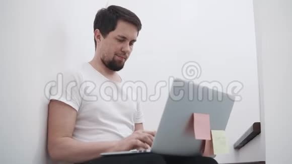 年轻人正坐在家里用笔记本电脑打字在网上交流视频的预览图