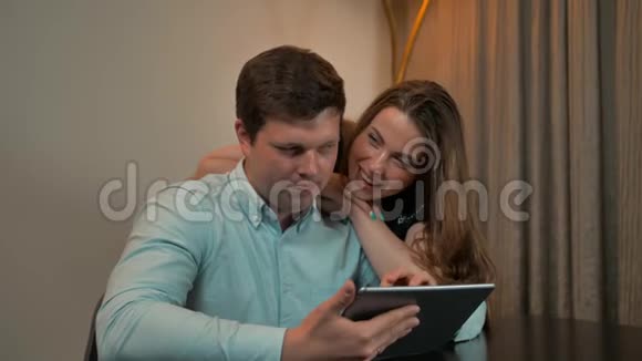 有魅力的夫妻男女在家里的平板电脑上冲浪视频的预览图