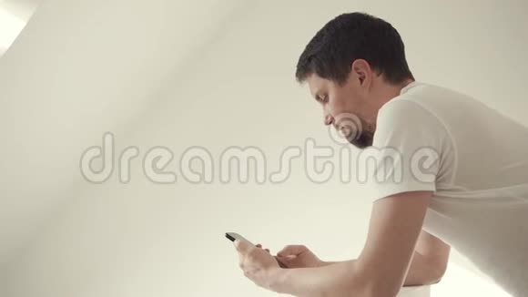 一个人在房间里用他的现代智能手机上网视频的预览图