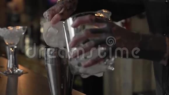 有纹身的年轻酒保把冰块放进鸡尾酒里视频的预览图