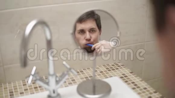 男人在洗手间的一面小镜子里刷牙的反应视频的预览图