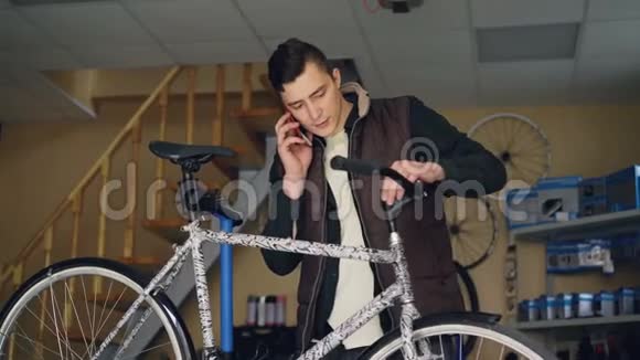 有魅力的年轻人开朗的机械师正在用手机和组装自行车把手人维修视频的预览图