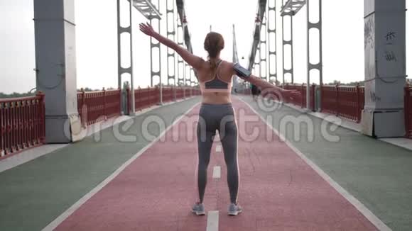 桥上女性伸展手臂的后视图视频的预览图