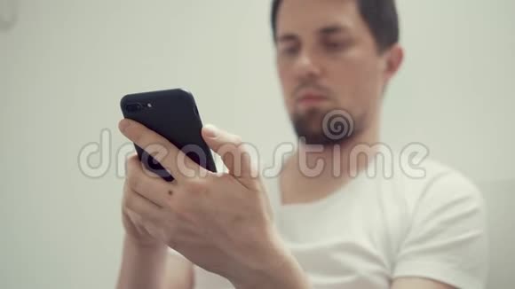在男性手中的黑色智能手机上男人的脸在背景中没有焦点视频的预览图