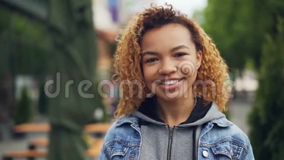 非裔美国学生的慢镜头肖像看着相机微笑着背景是美丽的绿色公园视频的预览图